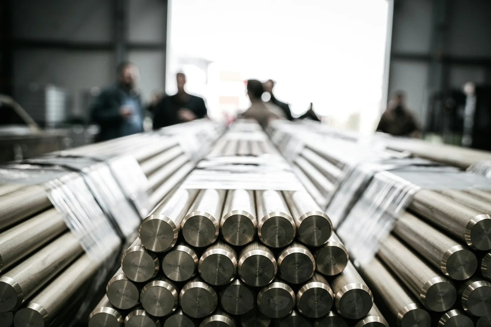 Metal rods with people in the background at a workshop; illustrative stock photo, not a Madhur facility or team